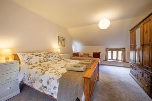 a bedroom with a bed with a dresser and a table at Converted stables and hayloft in former farmyard in Saint Briavels