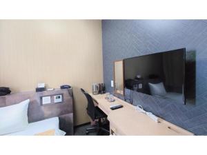 a hotel room with a desk with a large tv on the wall at Hotel Area One Oita - Vacation STAY 99740v in Oita