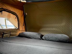 1 cama con 2 almohadas en una tienda de campaña en Embark on a journey through Maui with Aloha Glamp's jeep and rooftop tent allows you to discover diverse campgrounds, unveiling the island's beauty from unique perspectives each day, en Paia