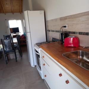 cocina con fregadero y nevera blanca en Cabañas Plottier-Neuquén en Plottier