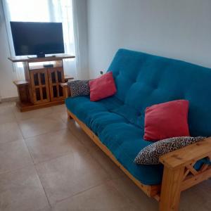 niebieska kanapa z czerwonymi poduszkami w salonie w obiekcie Cabañas Plottier-Neuquén w mieście Plottier