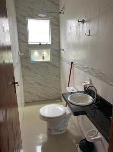 une salle de bain avec toilettes, lavabo et fenêtre dans l'établissement Casa Condomínio FRENTE PARA O MAR, à Praia Grande