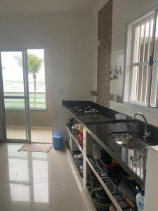 - une cuisine avec un plan de travail noir et un évier dans l'établissement Casa Condomínio FRENTE PARA O MAR, à Praia Grande