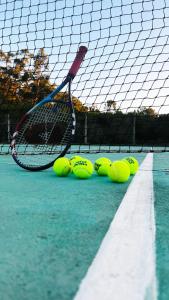 una raqueta de tenis y pelotas en una pista de tenis en Casa Lobo, en La Pedrera