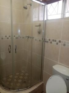 a shower with a glass door next to a toilet at Happy days in Amanzimtoti