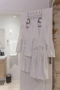 - un ensemble de vêtements blancs sur des cintres dans la salle de bains dans l'établissement Le Refuge, T2 élégant Aéroport d'Orly, à Athis-Mons