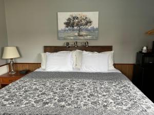 a bed with white pillows and a picture on the wall at Pleasant Valley Resort in Arcadia