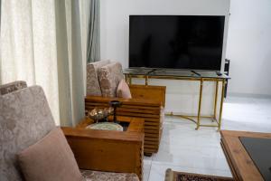uma sala de estar com 2 cadeiras e uma televisão de ecrã plano em Gulberg Luxe Living 2-BR Apartment em Lahore