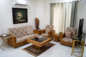 uma sala de estar com um sofá e duas cadeiras em Gulberg Luxe Living 2-BR Apartment em Lahore