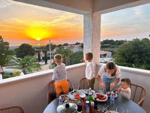 a woman and three children sitting at a table on a balcony at Sunshinewilla com - amazing sea view - private pool - 4 bedrooms - 3 bathrooms - workout in Kaštelir