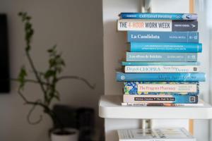 a stack of books sitting on top of a shelf at Inviting 2BD Flat - 1 Min from Deptford Station! in London