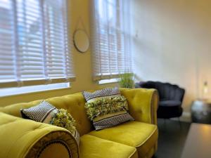 a yellow couch with pillows on it in a living room at Bristol City Stays - Cabot Circus in Bristol