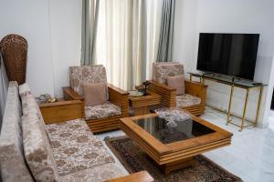 salon z kanapami i telewizorem z płaskim ekranem w obiekcie Gulberg Luxe Living 2-BR Apartment w mieście Lahaur