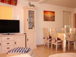 a dining room with a table with chairs and a television at Doppelhaushälfte Dünenrose, Glowe in Glowe