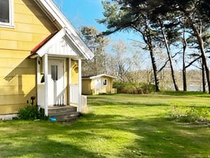 ein gelbes Haus mit einer weißen Tür und einem Hof in der Unterkunft Holiday home LAHOLM IX in Laholm