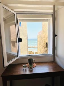 een raam met uitzicht op de oceaan vanaf een tafel bij Ocean Home in Essaouira