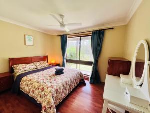 1 dormitorio con cama y ventana en Macyland, en Woollamia