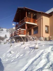 a building with snow on the ground in front of it at Cabana Gabriel Bucovina in Şaru Bucovinei