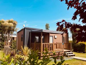 ein kleines Haus mit einer Veranda und einer Terrasse in der Unterkunft Camping le Rivage in Quettehou