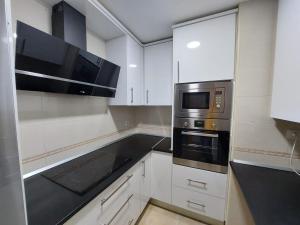 a kitchen with white cabinets and a microwave at El rinconcito de alicia in Arévalo