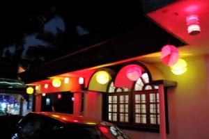 a building with red lights and a car parked in front at Ushuaia- Entire villa, nestled in nature's embrace in Navelim