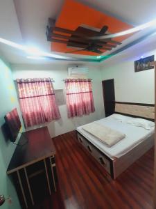 a bedroom with a bed and a table and a ceiling at OYO Galaxy Lodge in Partūr