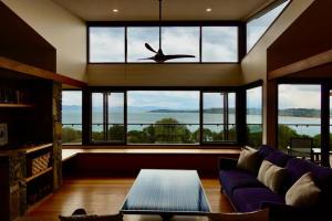 uma sala de estar com um sofá roxo e janelas grandes em Eco Waterfront Seclusion - Carlton Bluff House em Primrose Sands