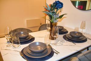 a table with plates and glasses and a vase with flowers at AP- Luxury Apt nxt to o2 Academy in Birmingham