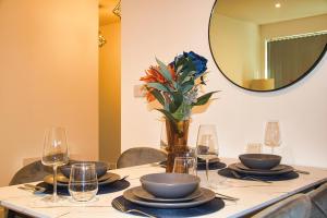 a table with plates and glasses and a vase with flowers at AP- Luxury Apt nxt to o2 Academy in Birmingham