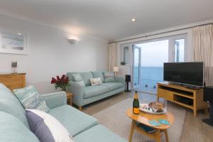 a living room with a blue couch and a television at Wavetop in St Ives