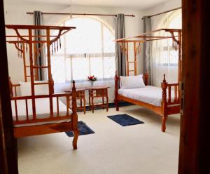 een slaapkamer met 2 bedden, een tafel en een raam bij Imani House in Malindi