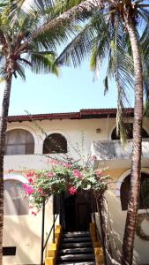 een gebouw met palmbomen en bloemen ervoor bij Imani House in Malindi