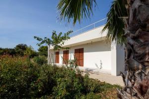 a white house with a palm tree in the foreground at Santa Lucia - Villa&Boat in Turanj