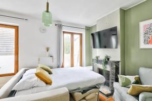 1 dormitorio con 1 cama, TV y sofá en Charmant appartement T3 avec joli balcon terrasse, en Créteil