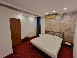 a bedroom with a white bed and a stone wall at Pensiunea Escape in Iaşi
