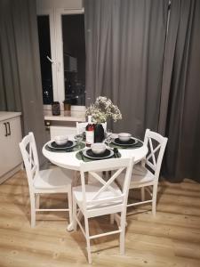 a white dining room table with white chairs and a white table and chairsktop at Czwarte Piętro in Zamość