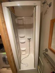 W łazience ze szklanymi drzwiami znajduje się biały prysznic. w obiekcie Location montagne le Revard w mieście Pugny-Chatenod