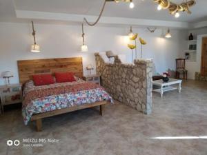 ein Schlafzimmer mit einem Bett und einer Steinmauer in der Unterkunft Hotelmirador las grullas in Montmesa