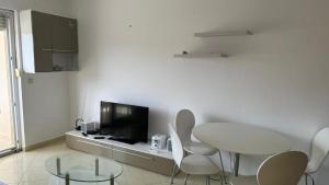 a white room with a table and chairs and a tv at Apartment Paska in Novalja