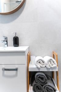 ein Badezimmer mit Handtüchern auf einem Regal unter einem Waschbecken in der Unterkunft New cosy apartments with private parking in Opatija