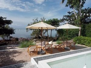 un patio con sillas y sombrillas y una piscina en Nest Sense Resort, en Ko Chang