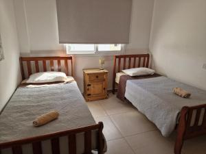 a bedroom with two beds and a nightstand and a window at Oceania Bay Village in Pyla