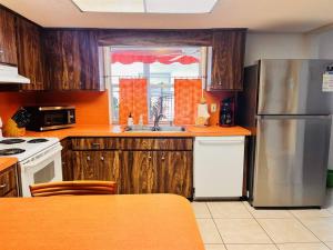 La cuisine est équipée d'armoires en bois et d'un réfrigérateur en acier inoxydable. dans l'établissement Beach, Sand, Firepit and Pool, à Clearwater Beach