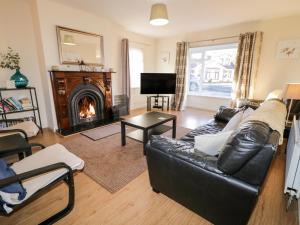 a living room with a black leather couch and a fireplace at Coneyville in Derry Londonderry