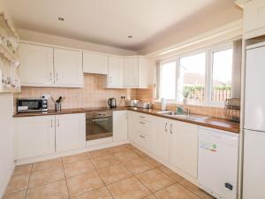a kitchen with white cabinets and a large window at Coneyville in Derry Londonderry