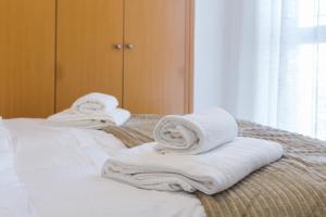 una pila de toallas sentadas encima de una cama en Piso familiar cerca del centro, AC y Wifi gratis (PA), en Valencia