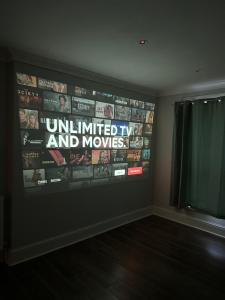a room with a wall with a television with a bunch of videos at Liverpool Street Green Bedroom in London