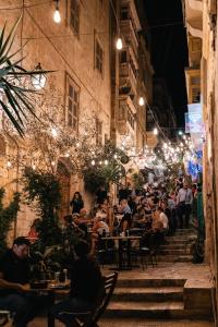 a crowd of people sitting at tables in an alley at night at Valletta Stylish 2 Beds Flat in Valletta