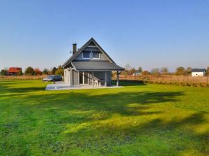 a small house in a field with a grass yard at Holiday home with private garden close to the lake in Osieki