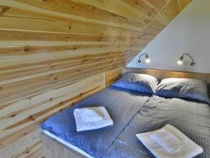 a bed in a room with a wooden wall at Holiday home with private garden close to the lake in Osieki